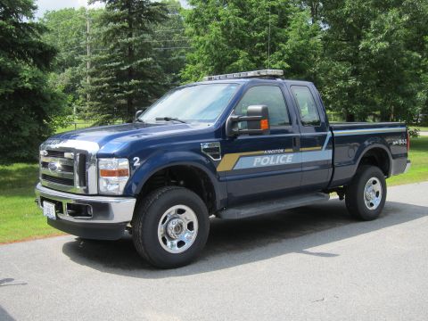 2001 Ford Crown Victoria - Kingston Police Ford F-350 Super Duty truck parked on an asphalt road with trees in the background.