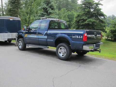 2001 Ford Crown Victoria - A blue Ford F-Series pickup truck, marked as "Kingston Police", is parked next to a dark blue trailer.