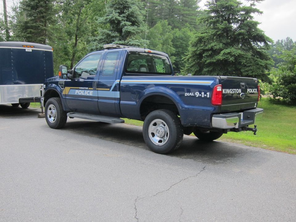 Blue Ford F-Series pickup truck with police markings and a trailer