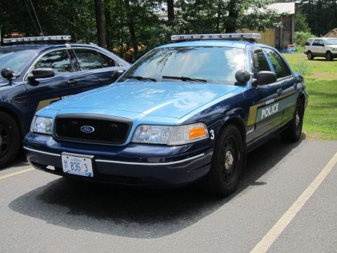 2001 Ford Crown Victoria - A police car with a light bar is parked in a lot next to another police vehicle.