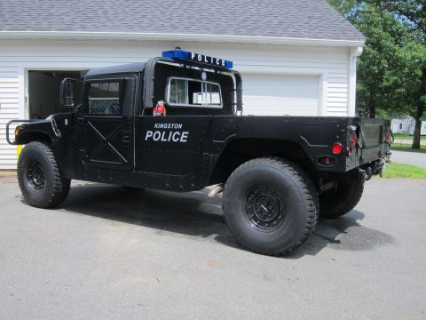 2001 Ford Crown Victoria - A black Humvee, marked as Kingston Police, is parked outside a residential garage.