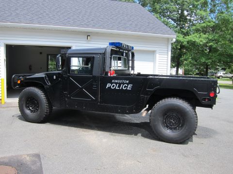 2001 Ford Crown Victoria - A black Humvee police vehicle is parked in front of a garage.