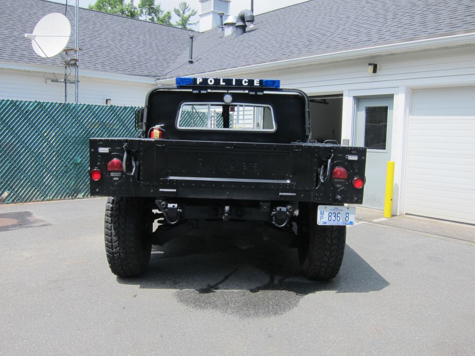 Black military-style truck marked POLICE viewed from the rear