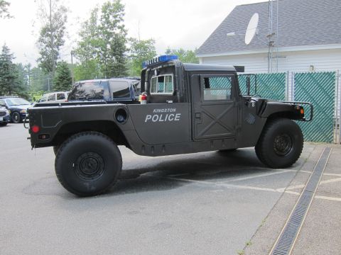 2001 Ford Crown Victoria - A matte black Hummer H1 is parked outside a building.