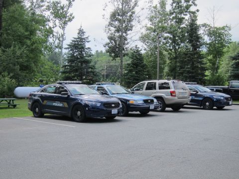 2001 Ford Crown Victoria - Several vehicles are parked in an outdoor lot, including a dark sedan and a white SUV.