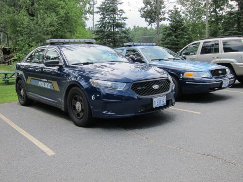 2001 Ford Crown Victoria - A dark blue 2001 Ford Crown Victoria police car is parked in a lot, alongside other vehicles.