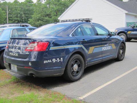 2001 Ford Crown Victoria - A Kingston Police vehicle is parked next to another police car, with a building in the background.