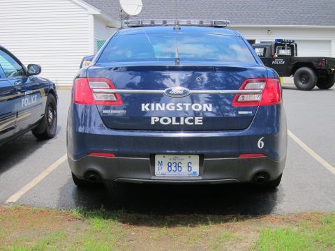 2001 Ford Crown Victoria - A dark blue Ford sedan, marked as Kingston Police, is parked in a lot next to another police vehicle.