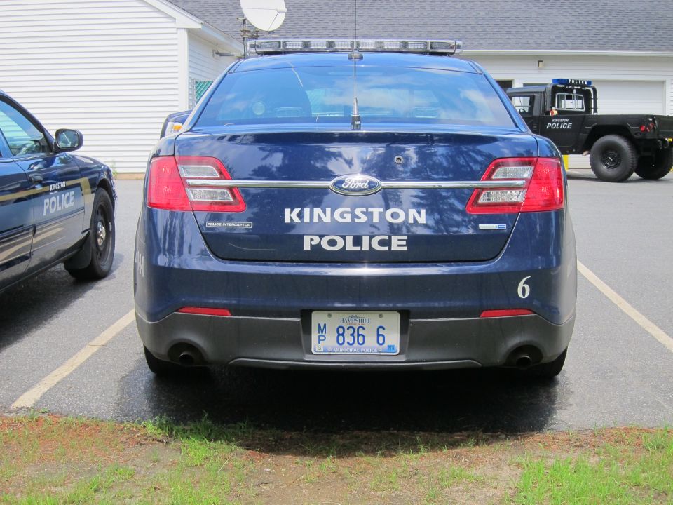 Rear view of a dark blue Ford sedan with 'KINGSTON POLICE' text and license plate M 836 6