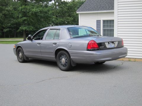 2001 Ford Crown Victoria - A gray Ford Crown Victoria Police Interceptor is parked on asphalt in front of a white building.