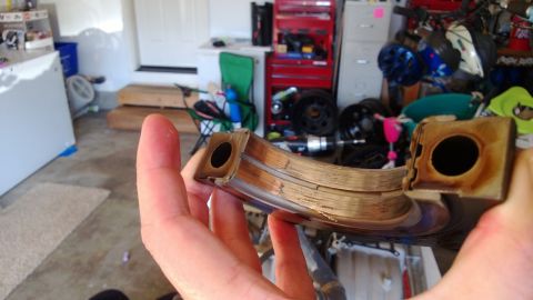 1994 Ford Bronco - A close-up of a worn engine bearing, showing significant damage and scoring from use.