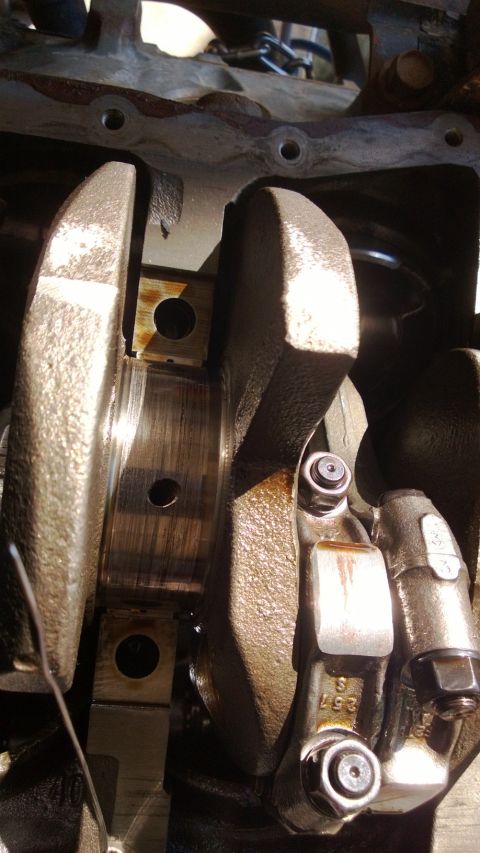 1994 Ford Bronco - Close-up view of an engine's crankshaft and connecting rod, showing signs of wear and oil residue.