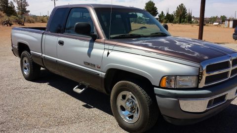 1995 Ford Bronco - A two-tone Dodge Ram pickup truck is shown from a three-quarter front angle, with visible wear on its hood.