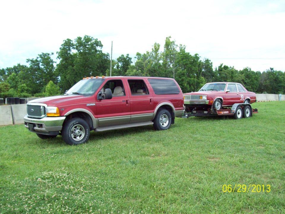 Red SUV towing a red car on a trailer, with a date stamp of 06/29/2013
