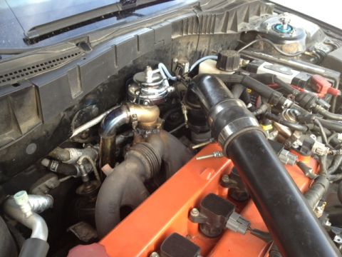 1987 Ford Bronco - Engine bay detail showing a turbocharger and wastegate assembly, with an orange valve cover visible.