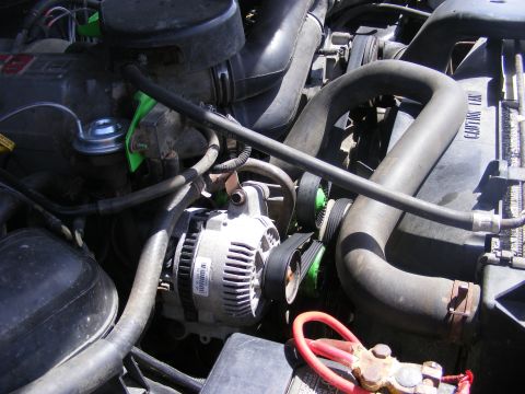 1996 Ford Bronco - Close-up view of an alternator and associated engine parts within a vehicle's engine compartment.