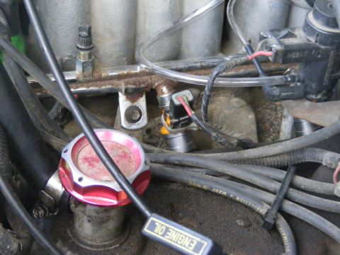 1996 Ford Bronco - A detailed view of engine components, including the fuel rail and an aftermarket oil cap.