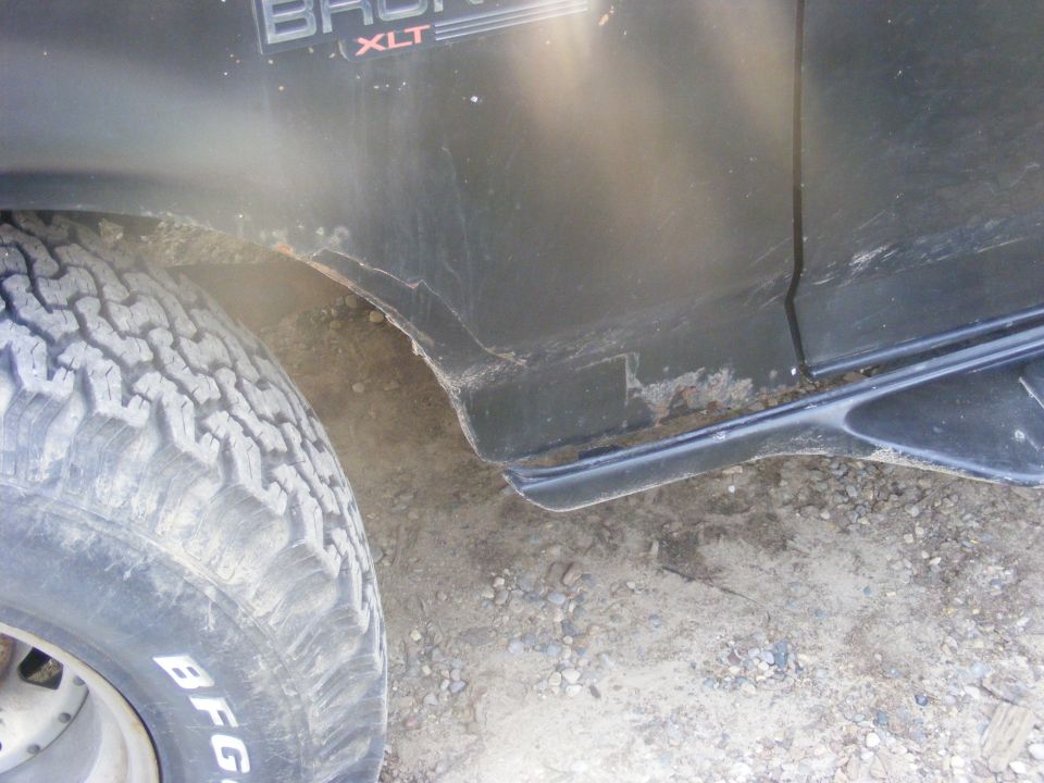 Black 1996 Ford Bronco XLT side view showing rust near the rear wheel well