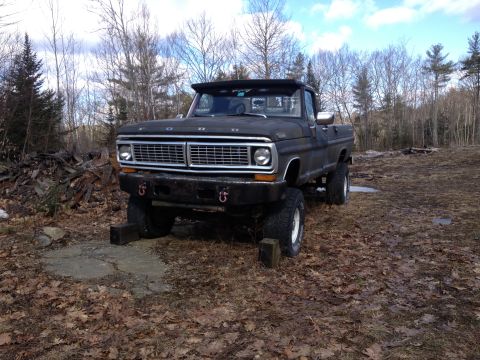 1979 Ford Bronco - A black Ford truck sits on a dirt lot with trees in the background.