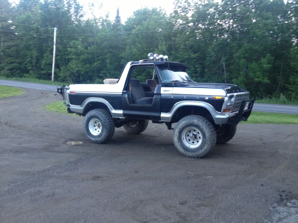 Lifted black and white Ford Bronco with off-road tires and aftermarket front bumper