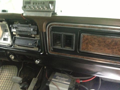 1979 Ford Bronco - The interior of a 1979 Ford Bronco shows its dashboard with wood grain accents and various electronic accessories.
