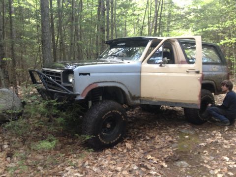 1979 Ford Bronco - This modified Ford Bronco, likely a 1978 model, sits in a forest with its door open.