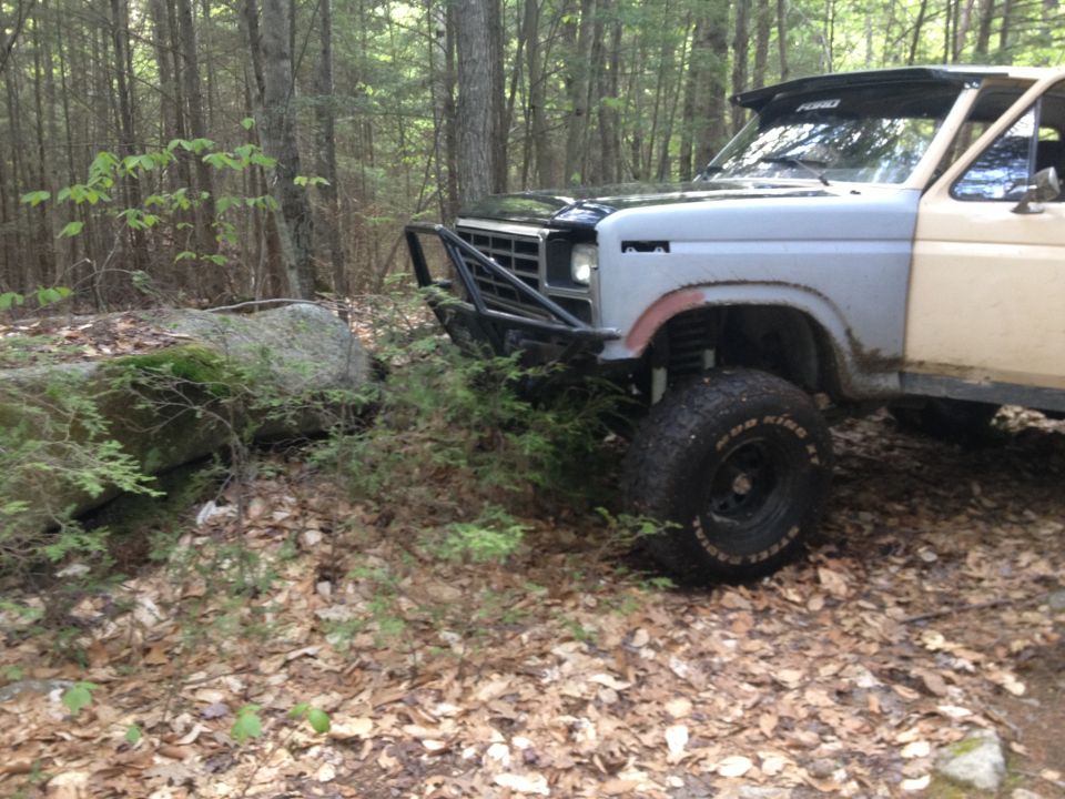 Modified pickup truck with aftermarket bumper and off-road tires parked in woods