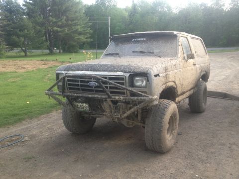 1979 Ford Bronco - This heavily modified Ford Bronco is covered in mud, suggesting recent off-road use. The year is estimated based on its body style.