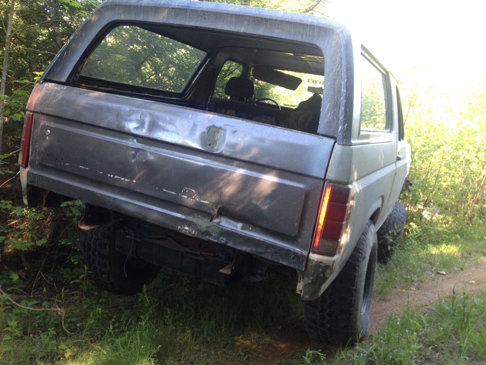 Rear view of a gray 1979 Ford Bronco with damage to the tailgate