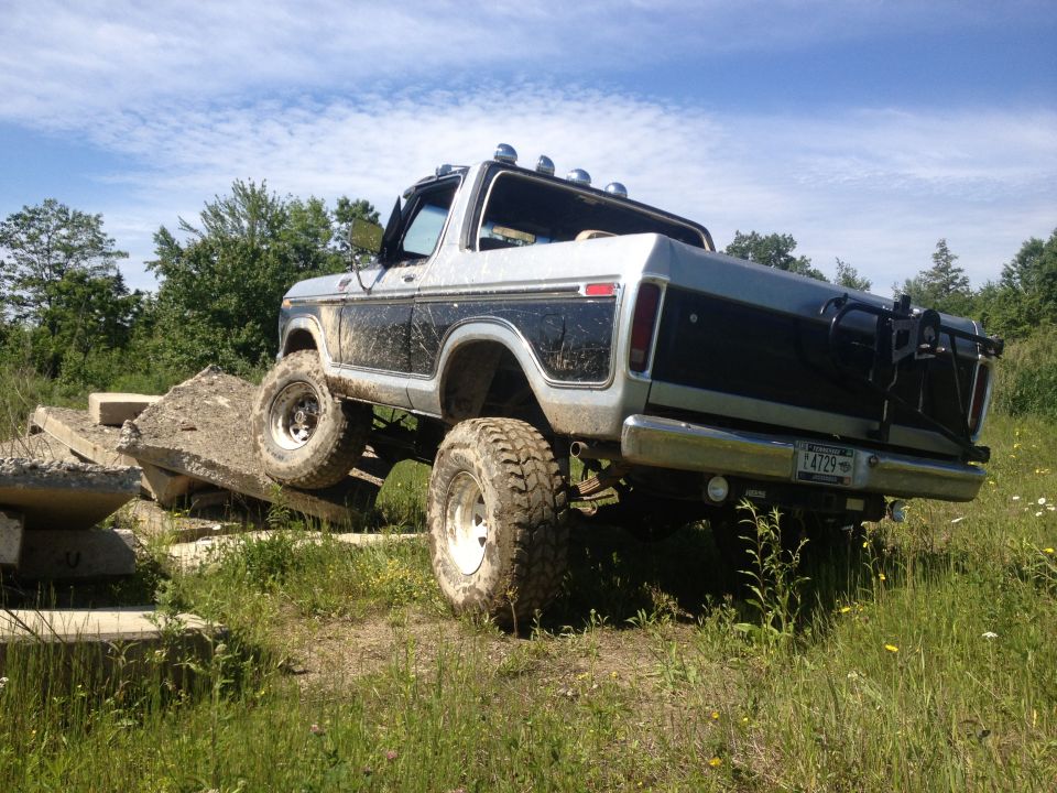 Lifted Ford Bronco with mud on it, driving over concrete obstacles. License plate L4729