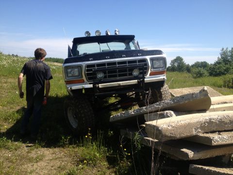 1979 Ford Bronco - A man watches as a lifted 1979 Ford Bronco navigates an obstacle course made of concrete slabs.