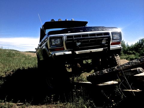 1979 Ford Bronco - This black 1979 Ford Bronco navigates a challenging off-road obstacle course under a clear blue sky.