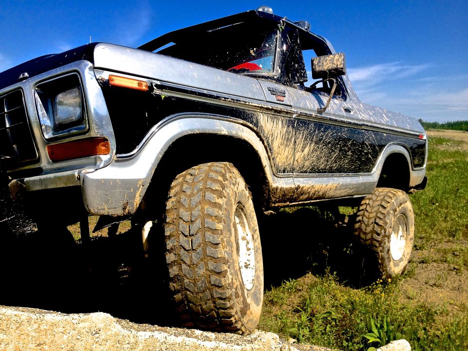 Mud-splattered 1979 Ford Bronco, 3/4 front view, two-tone black and silver
