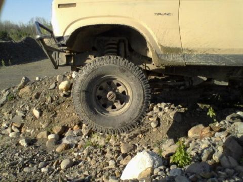 1979 Ford Bronco - A tan 1978 Ford Bronco is shown from a 3/4 front angle, navigating a rocky, off-road environment.