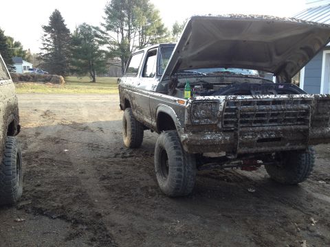 1979 Ford Bronco - A muddy 1978 Ford Bronco sits with its hood open, beside another vehicle on a dirt track.