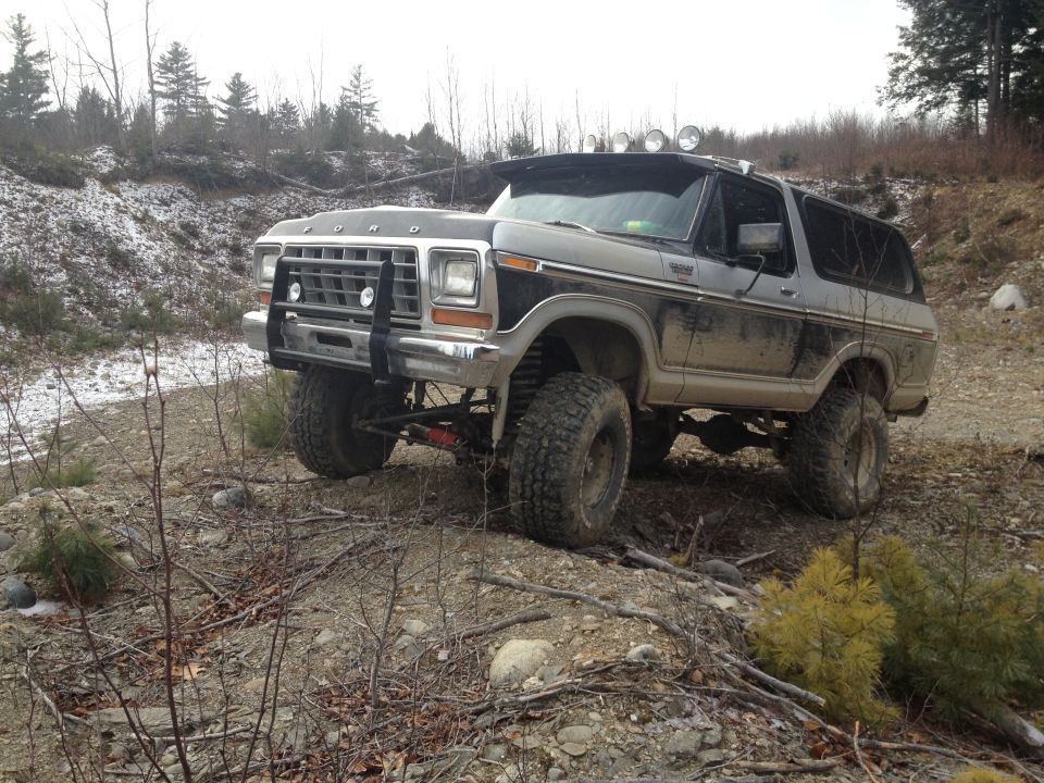 Two-tone Ford Bronco with off-road tires and brush guard on a dirt path