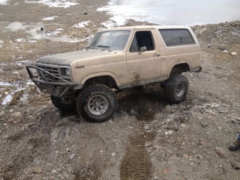 1979 Ford Bronco - This tan 1979 Ford Bronco is navigating a rocky, muddy terrain.
