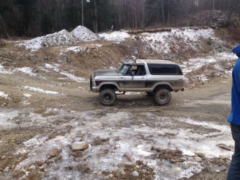 1979 Ford Bronco - This lifted Ford Bronco is parked on a dirt road with snow and ice on the ground.