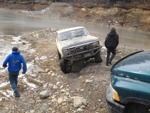 1979 Ford Bronco - A 1979 Ford Bronco navigates a challenging off-road course with two people observing.