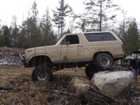 1979 Ford Bronco - A tan Ford Bronco navigates a rocky terrain, with another vehicle and a person visible in the background.