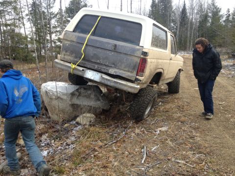 1979 Ford Bronco - A 1979 Ford Bronco is stuck on rocks, with two people observing the situation.