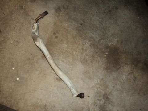 2004 Mercury Grand Marquis - A detached exhaust pipe with a protective heat shield lies on a concrete surface.