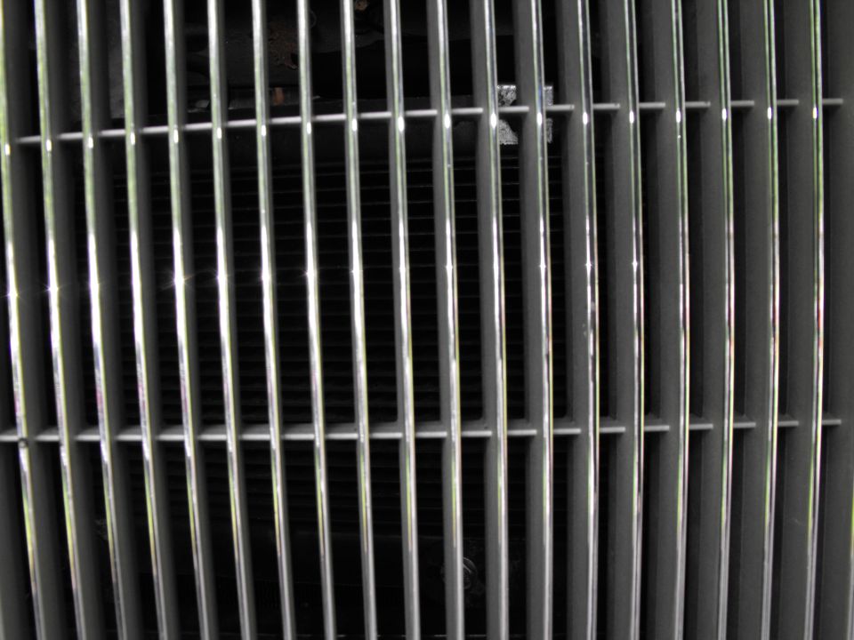 Close-up of vertical chrome grille bars with dark slats and radiator visible behind