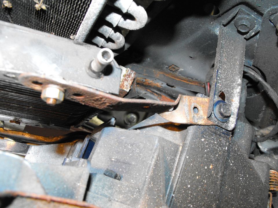 Last mount was the passenger's side lower bracket. I simply twisted strap steel 90 degrees allowing it be bolted to the bottom of one of the plastic headlight buckets using one of the stock bucket bolts. Cooler fully secured in four places, centered in the wind stream of the grill and plenty of access to the pipe nipples to get the hoses and clamps on.