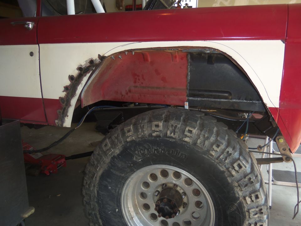 1968 Ford Bronco rear fender undergoing repair, showing cut metal and new patch panel