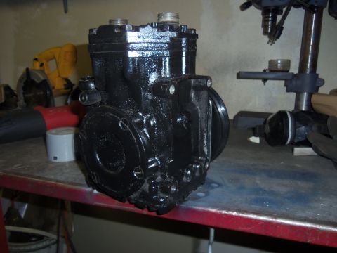 1968 Ford Bronco - Air conditioning compressor part shown on a workbench with tools in the background.