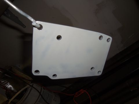 1968 Ford Bronco - A white metal plate, possibly a mounting bracket, hangs from a rod in a workshop setting with visible tools and wires.