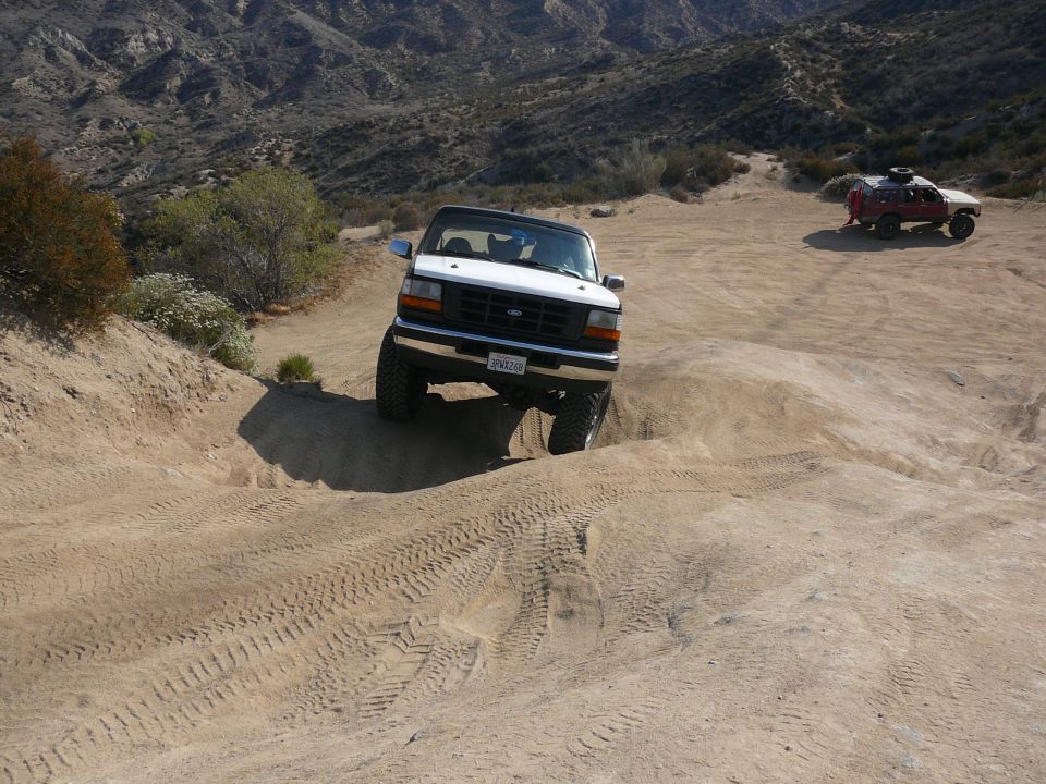 White 1995 Ford Bronco climbing a dirt hill off-road