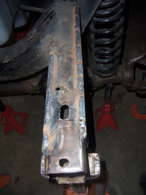 1968 Ford Bronco - Close-up of welded frame plates and suspension components, supported by jack stands.