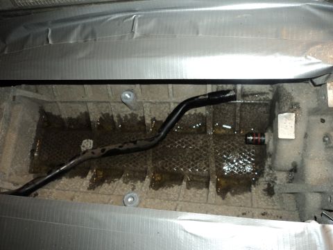 2004 Mercury Grand Marquis - Underside view of an engine oil pan showing a bent pipe and signs of fluid leakage.